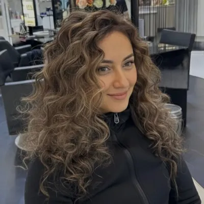An elegant color transformation on curly hair. The highlights add beautiful dimension and a luxury finish, making each curl stand out.