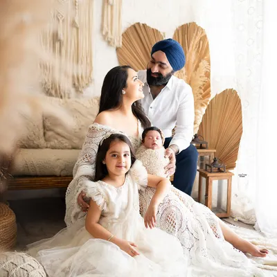 Welcoming a new baby is a milestone for the whole family. This beautiful portrait captures the love and excitement of parents and a big sister meeting the newest member.