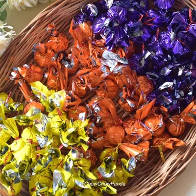 A basket full of my homemade chocolates, ready for a corporate order. They are individually wrapped in bright yellow, orange, and purple foil.