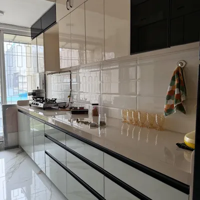 A close-up of a finished modular kitchen. This view highlights the glossy, handleless drawers, the white subway tile backsplash, and the spacious countertop, perfect for meal prep.