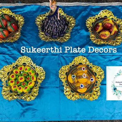 A set of five decorative plates with a blue and gold theme, featuring arranged sweets and a doll centerpiece.