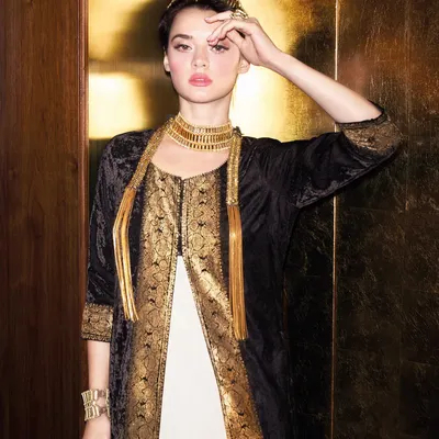 A high-fashion look for a Biba campaign, featuring a black and gold velvet jacket layered over a white dress. The styling is elevated with a statement gold choker and headband, creating a look of modern Indian luxury.