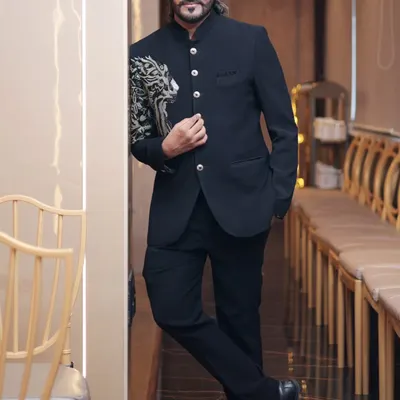 A full-length view of our black Jodhpuri suit on a client. This image shows how the tailored fit and striking shoulder embroidery create a powerful silhouette, perfect for a groom or guest of honor.