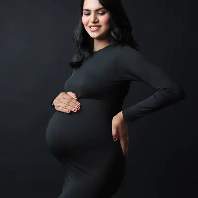 A classic solo maternity portrait. The simple black dress and dark background create a stunning, high-contrast image that beautifully highlights the baby bump.