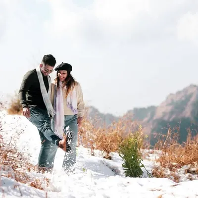 A playful moment captured in the snow. I believe pre-wedding shoots should be fun, and this candid shot of them kicking up snow shows their joyful and carefree connection amidst a stunning mountain landscape.