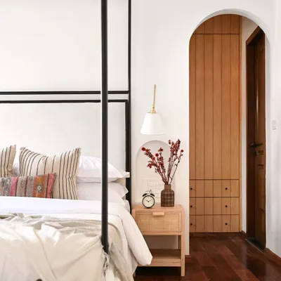 This detail shot from the Modern Spanish master bedroom shows the arched doorway I added to lead into the new walk-in closet. The arch mirrors other architectural details in the home, and the custom rattan bedside table adds natural texture.