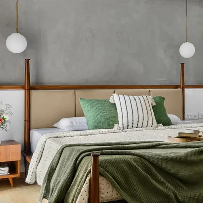 For the 'Poorna' primary room, we designed this half-poster bed to provide aesthetic appeal without obstructing the view of the TV, which is discreetly housed in the wardrobe. The concrete-finish texture wall adds a modern touch.