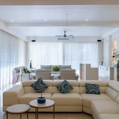 An expansive living area designed for seamless flow, where a cream leather sectional and patterned accent pillows create distinct zones for relaxation and conversation within a bright, open-concept layout.