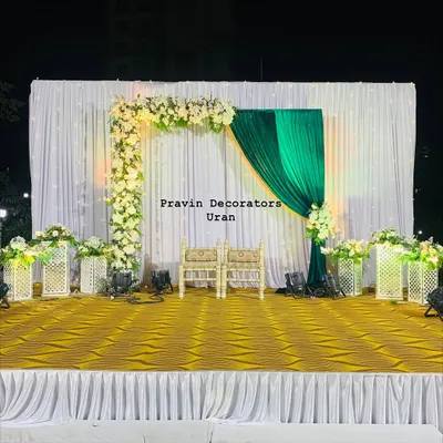 A classic stage setup for a Tilak ceremony. The design features an elegant floral arch of white roses against a backdrop of white and rich green drapes, creating a fresh and traditional look.