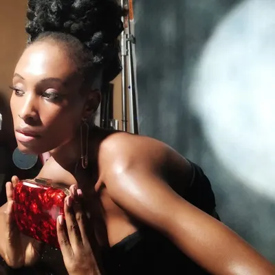 A behind-the-scenes shot from a beauty editorial, showing the final look under studio lighting. The focus was on creating a glowing complexion and a sculpted high-bun hairstyle to complement the model's features and the high-fashion concept.