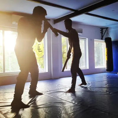 A silhouette of a personal training session in Kali stick fighting. This discipline is an effective tool for self-defense, teaching coordination, distance management, and weapon handling.