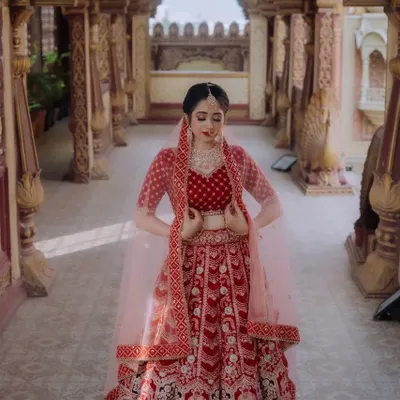 A stunning red bridal lehenga, a timeless choice for any bride. This piece features beautiful doli and elephant motifs embroidered all over, telling a story of tradition and celebration. The matching blouse and dupatta complete this royal look.