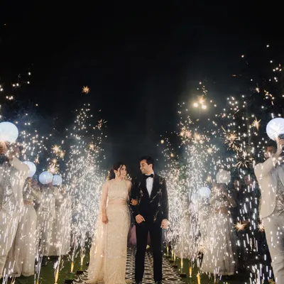 A spectacular sangeet night entrance. The couple walks down an aisle flanked by friends and dazzling cold-pyro sparklers, capturing the high energy and magical atmosphere of the celebration.
