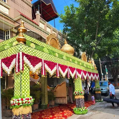 A complete view of a traditional wedding *chappara* I built. The structure is made from woven coconut leaves with a red and white flower border, and the pillars are decorated with sugarcane and flower bouquets.