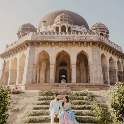 A majestic shot of a couple seated on the steps of a grand monument. This image perfectly captures the scale and romance of a heritage pre-wedding shoot in Delhi.