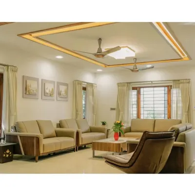 This view of the living room highlights the custom ceiling design with integrated cove lighting, which provides a soft, ambient glow. The layout is planned for conversation, with comfortable seating and large windows framed by simple curtains to maximize natural light.