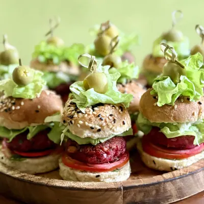 A closer look at my mini sliders, showcasing the freshly baked seeded buns, vibrant beetroot patty, crisp lettuce, and a juicy tomato slice. Each one is secured with an olive pick, ready to be enjoyed.
