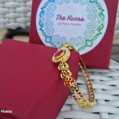 A side view of the "Ada" gold-plated Jadau bracelet. This angle highlights the colourful stones set in heart-shaped designs along the band.