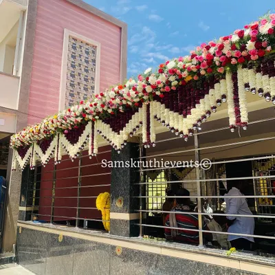 An elaborate floral decoration for a temple exterior. We used thick garlands of white, red, and pink flowers to create a festive canopy over the entrance for a special temple event.