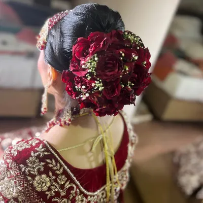 A perfect view of a classic bridal bun, decorated with a circle of fresh red roses and baby's breath. This style is timeless and provides a sturdy base for any dupatta or veil.