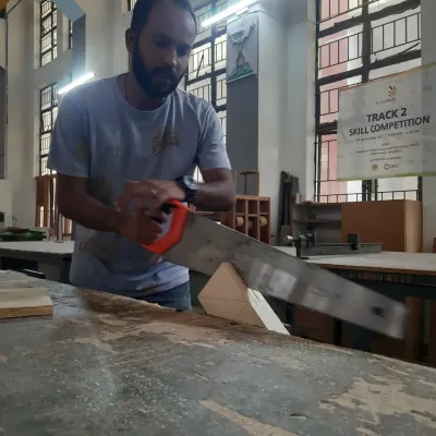 A student practices a fundamental skill, using a hand saw to make a precise cut. Mastering hand tools builds an intuitive understanding of how wood behaves.