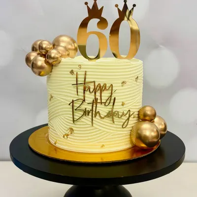 Celebrating 60 years in style! This elegant birthday cake features a beautiful wave texture, gold spheres, and a custom gold '60' topper with crowns. It’s designed to be a memorable centerpiece.
