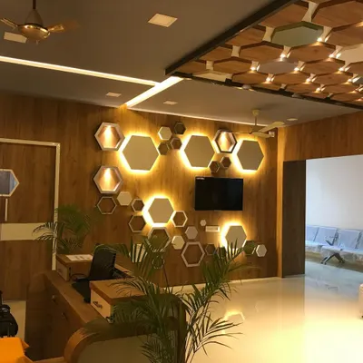 The reception of the Jeevannavar Skincare Clinic features a striking wall of backlit hexagonal mirrors and panels. This geometric design, combined with warm wood tones, creates a professional and stylish first impression.