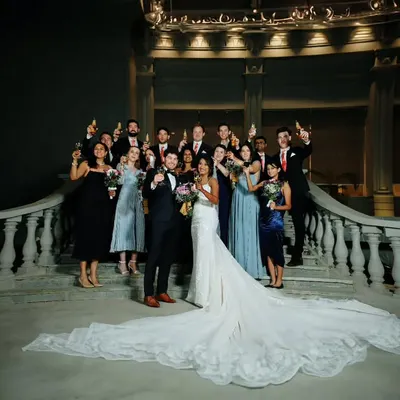 A beautiful group portrait from a cross-cultural wedding, with the bride in a stunning white gown with a long train, surrounded by her happy guests.