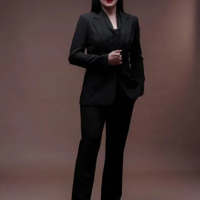 A powerful and professional full-length portrait. The clean, solid background and classic power suit create a look of authority and confidence, perfect for a corporate or executive profile.