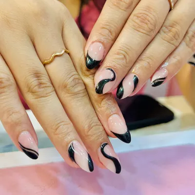 A chic and modern design featuring hand-painted black swirls on a sheer nude base. This abstract nail art is perfect for a minimalist yet stylish look on almond-shaped nails.
