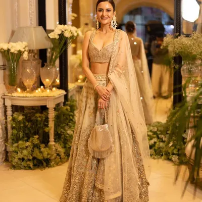 A full-length view of a client styled for a designer store launch, looking radiant in a golden lehenga. We created a sophisticated look with a clean bun and luminous makeup to match the elegance of the event.