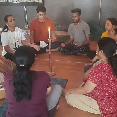 A group practicing Jyoti Trataka, a meditative practice of gazing at a candle flame. This ancient technique helps purify the eyes, improve concentration, and calm a restless mind.