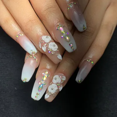 An absolutely stunning bridal look with long, square-shaped acrylics. This set features a white ombre base, intricate 3D white roses, and a lavish placement of iridescent Swarovski crystals.