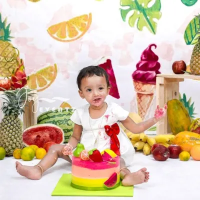 A vibrant and healthy twist on the classic cake smash. This fruit-themed session features a baby enjoying a colorful cake surrounded by fresh pineapples, watermelons, and other tropical fruits for a fun and unique first birthday shoot.