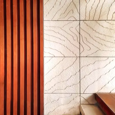 Our philosophy is that art takes nature as its model. This detail shot shows our custom wall art, where we contrasted the linear pattern of Burma Teak wood with an abstract organic design carved into Mint Gwalior stone, inspired by the veins of a leaf.
