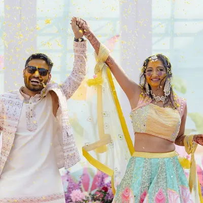 A golden beginning for a beautiful journey. This couple's Haldi was a burst of sunshine and celebration, and this shot captures their triumphant joy as they are showered with blessings and flower petals.