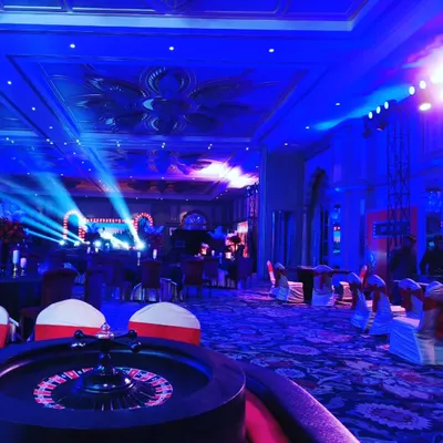 Let us bring the thrill of Las Vegas to your next corporate event. This image shows a full casino theme setup with dramatic lighting, a Roulette table in the foreground, and an exciting party atmosphere.