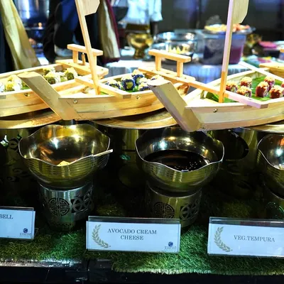 A creative presentation for our vegetarian sushi station. The sushi, including Asparagus Bell Pepper and Avocado Cream Cheese rolls, is served in miniature wooden boats, making the experience visually delightful and unique.