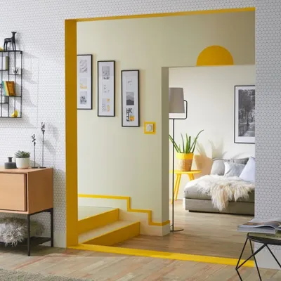 A simple line of bright yellow paint is used here to frame a doorway and stairs, adding a playful and modern architectural detail to an otherwise neutral space.