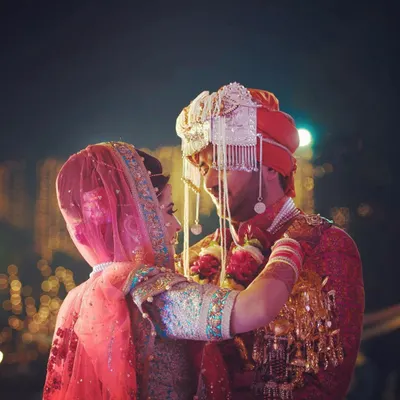 The Jaimala ceremony is a moment of mutual acceptance and joy. This candid capture freezes the instant the bride places the garland, focusing on the intimate look shared between the couple amidst the traditional setting.