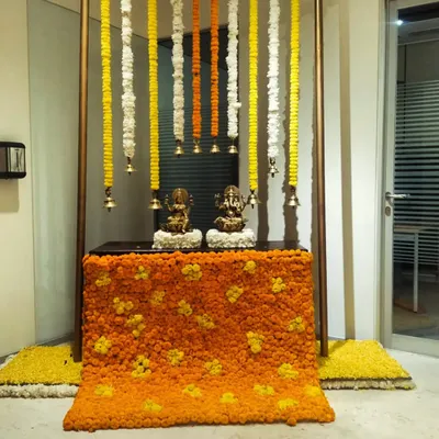 For a corporate Diwali celebration, we designed this sacred corner featuring idols of Ganesh and Lakshmi. The setup includes a backdrop of hanging marigold and tuberose garlands and a base covered in a floral carpet.