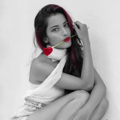 A classic color splash edit. The entire image is in black and white except for the model's red hair, lips, and the rose. This technique creates a powerful, high-contrast visual that is both romantic and artistic.