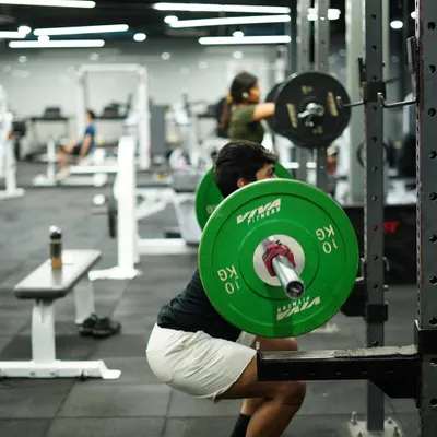 A member executes a heavy squat in the rack, a foundational exercise for building lower body strength and power. The focus and determination are clear.