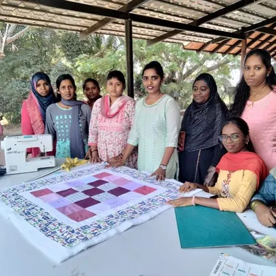 A proud group photo from our beginner quilt-making class, conducted for a local NGO, showcasing the finished project.