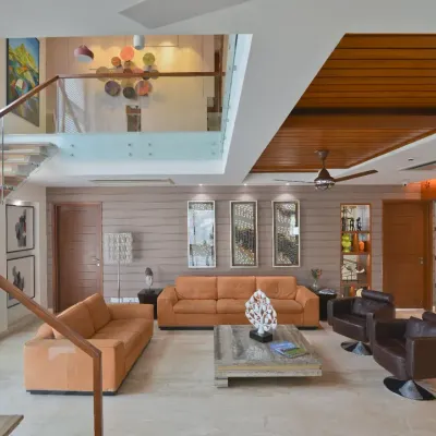 The drawing room of the Sobti Residence is characterized by a striking double-height volume. Abundant natural light enhances the openness of the space, while a floating wood-and-glass staircase adds architectural elegance.