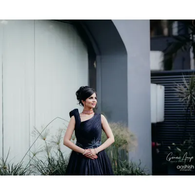 A full-length portrait showcasing a sophisticated cocktail look. The bride's elegant dark blue gown is paired with a chic updo and polished makeup, creating a look of modern grace and style.