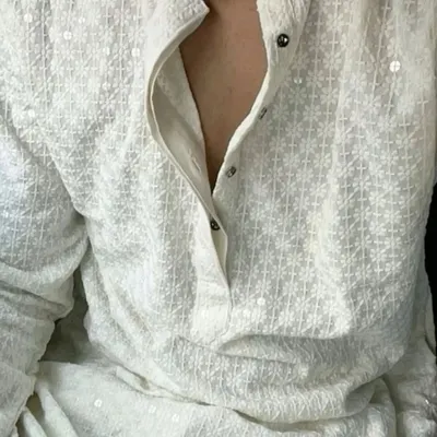 A close-up of a classic white chikankari kurta. The delicate threadwork and sequins make it a perfect choice for any festive occasion, from a puja to a Haldi ceremony.
