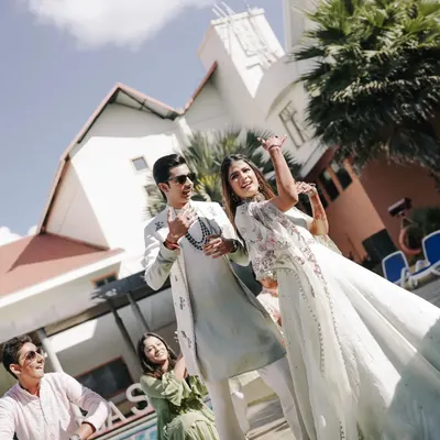 The dancing starts from the very first function. Here's the happy couple making their entry at the Haldi ceremony, surrounded by friends and family ready to dance.