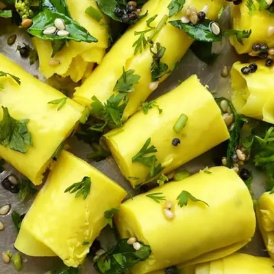 A close-up of our perfectly rolled Khandvi. You can see the delicate texture of the gram flour sheets, garnished with mustard seeds and fresh herbs. It's a light yet flavorful snack ideal for any time of day.