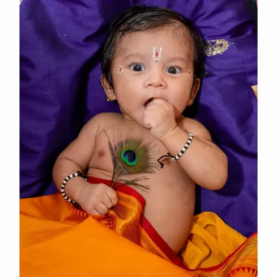 An adorable baby portrait from a Janmashtami themed shoot. This little 'Kanha' with his wide-eyed expression and a peacock feather is a perfect example of a creative and memorable baby photoshoot.